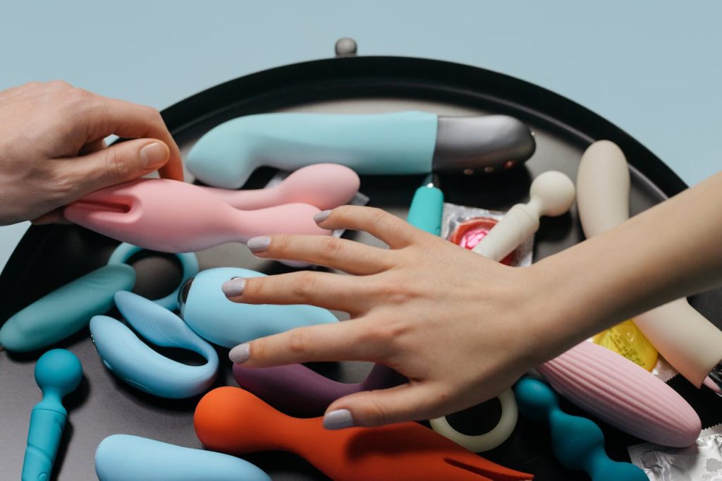 An assortment of vibrant sex toys with hands reaching for selection.